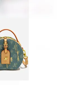 Dettaglio della borsa rotonda in denim blu con finiture in pelle e dettagli dorati