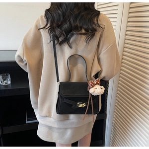 Close-up of black crossbody bag with golden hardware and cute bear charm detail