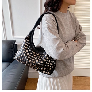 Gros plan d'un sac porté épaule noir en forme de croissant avec des clous métalliques