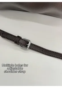 Détail de la bandoulière en cuir marron avec boucle argentée ajustable et perforations