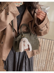 Detail of dark moss green shell bag with soft matte texture and cute plush rabbit charm