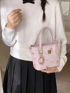 Borsa a secchiello in pelle rosa con stampa di coniglio e ciondolo su modella femminile