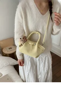 Pale yellow pleated bucket bag detail with double handles and cute plush bear charm