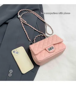 Detail view of pink quilted chain bag with gold metal handle and turn-lock closure