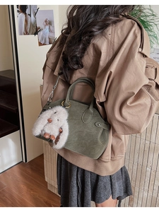 Detail of olive green leather handbag with plush bunny charm and sturdy handle