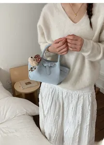 Detail of light blue bucket bag with pleated texture and a cute teddy bear charm