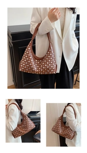 Détail d'un sac hobo marron vintage avec rivets argentés et forme élégante en demi-lune