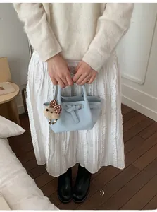 Détail d'un sac seau plissé bleu clair avec breloque ours et boucle métallique