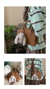 Detail of brown leather tote bag with soft grey rabbit pendant and metal handle