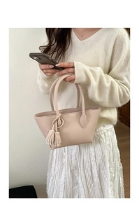 Detail of light pink pebble grain handbag with elegant tassel and double handles