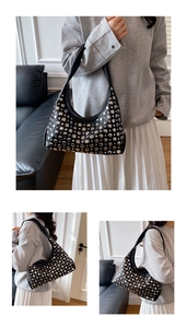 Dettaglio della borsa tote nera in similpelle con borchie metalliche e design a luna