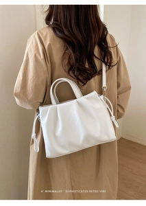 Détail d'un sac cabas blanc plissé avec cordons, porté avec un trench-coat kaki chic
