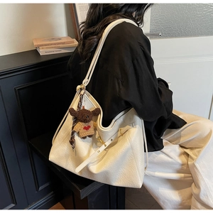 Detail of cream large tote bag with lychee texture and cute puppy plush pendant