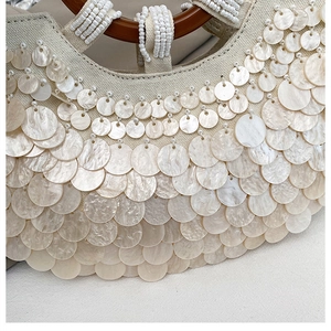 Close-up of handmade sequin shoulder bag with shell texture and wooden ring handle