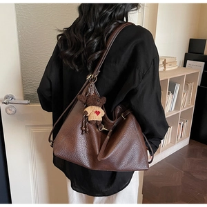 Detail of large brown lychee pattern tote bag with cute bear charm and vintage buckles