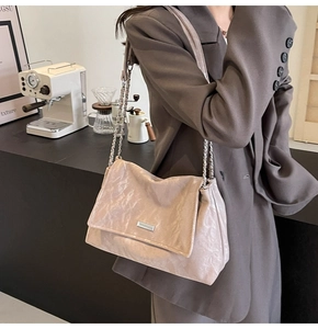 Dettaglio borsa in pelle plissettata beige con catena argento e placca logo in metallo