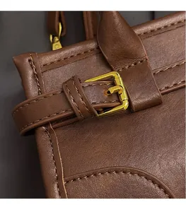 Close-up of brown leather handbag with precision stitching and golden buckle detail