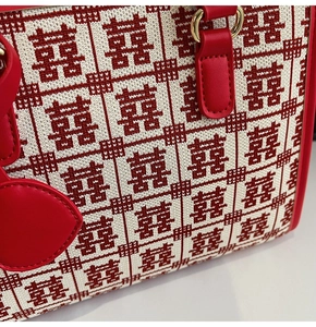 Dettaglio del tessuto intrecciato con motivo Xi rosso e manici in pelle della borsa