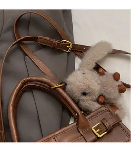Detail of vintage brown tote with golden buckle and grey rabbit plush pendant