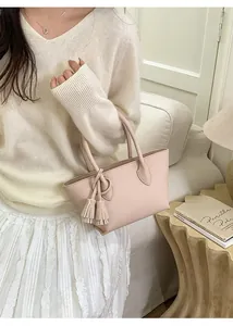 Close-up of a pale pink leather tote bag with tassels in a cozy minimalist interior