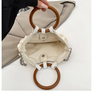 Detail of sequined handbag featuring wooden circular handles and magnetic closure