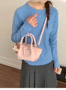Detail of light pink bucket bag with soft pleated texture and cute teddy bear pendant