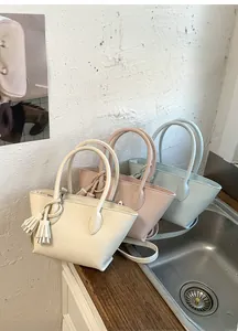 Detail view of stylish tassel bucket bags in cream, light pink, and soft blue colors