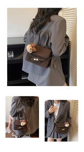 Detail of dark brown matte leather bag with a cute bear charm and golden metal clasp