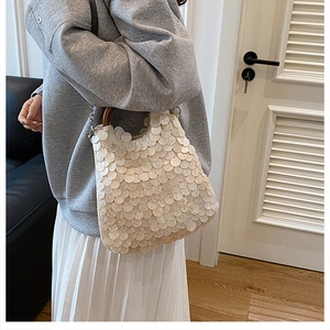 Detailed macro view of white sequin scales and rustic round wooden handles on a shoulder bag