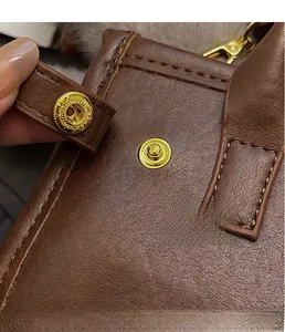 Detailed macro view of the premium brown leather bag with golden magnetic clasp and stitching