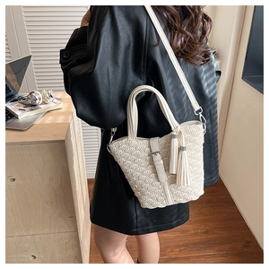 Close-up of cream pleated shoulder bag with decorative tassels in a lifestyle setting
