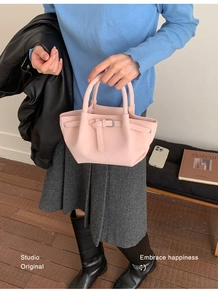 Detail of light pink bucket bag with silver buckle and textured synthetic leather
