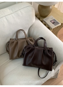 Gros plan de sacs cabas plissés café et kaki posés sur un canapé en tissu douillet