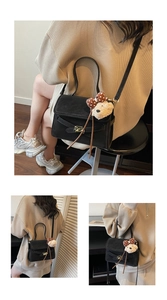 Detail of black suede shoulder bag with metallic buckle and cute puppy charm accessory