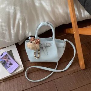 Détail d'un sac seau en cuir bleu clair avec motif lychee et charm ours en peluche