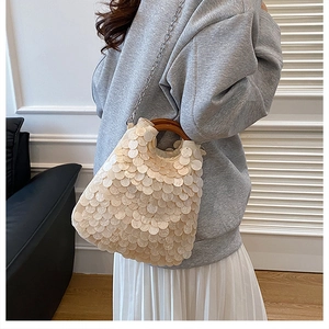 Close-up of handmade sequin handbag with wooden ring handle and metal chain strap