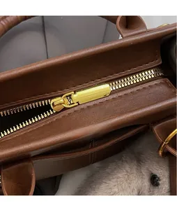 Close-up of polished gold-tone hardware and zipper on dark brown leather handbag
