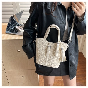 Detailed macro view of off-white pleated bucket bag with tassel charms and crossbody strap
