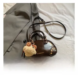 Brown leather crossbody pillow bag with gold studs and a cute plush bear charm detail