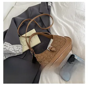 Detailed close-up of brown textured woven faux leather shoulder bag with metal buckle