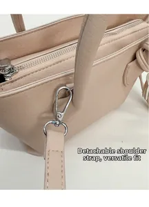 Detail of beige lychee grain leather handbag featuring detachable strap and silver hardware