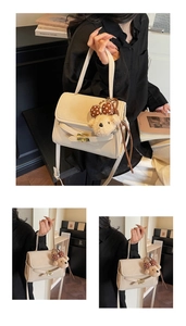 Detail view of cream shoulder bag with plush bear pendant and leather flap buckle closure