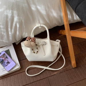 Détail du sac seau blanc chaud avec texture plissée et breloque décorative en peluche