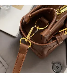 Close-up of golden swivel hook hardware and stitching on brown leather handbag