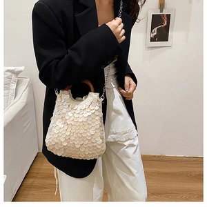 Detail of sequined shoulder bag with round wooden handle and metallic chain strap