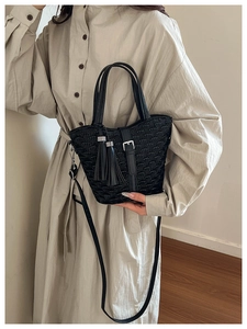 Detail of black pleated crossbody bag with fish scale texture and elegant double tassels