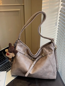 Retro brown large capacity tote bag with bear charm on a chair in a cozy office setting