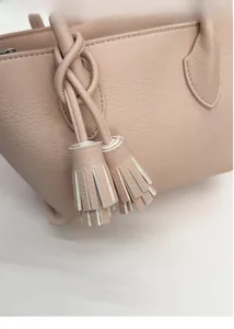 Detail of lychee pattern leather and elegant tassel pendant on the pink bucket handbag