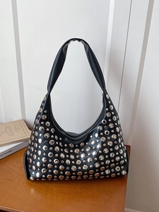 Sac hobo noir en cuir avec rivets argentés et poignée sur un bureau en bois