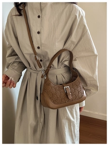 Detail view of brown embossed saddle bag with silver buckle worn by a model